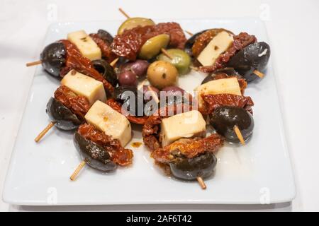 Schwarze Oliven, getrocknete Tomaten und Käse am Spieß, eine Tapas Teller. Stockfoto