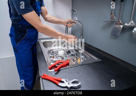 Glückliche junge männliche Klempner zur Festsetzung der Wasserhahn in der Küche Stockfoto