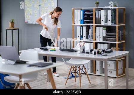 Volle Länge des Weiblichen Hausmeister wischen Stock im Büro Stockfoto