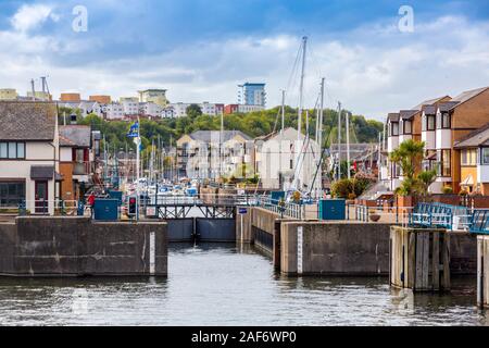 Der Eingang zum Kais Penarth Marina, Cardiff Bay mit attraktiven neuen Gehäuse Architektur am Kai und Hügel jenseits, Glamorgan, Wales, Großbritannien Stockfoto