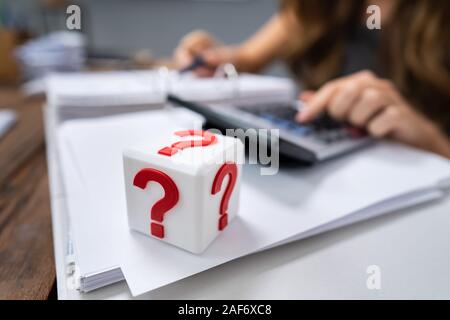 Kubische Block mit roten Fragezeichen Zeichen auf Schreibtisch Stockfoto