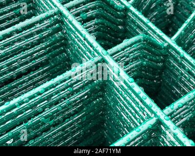 Regen fällt auf grün gefärbten Metallgitter. Stockfoto