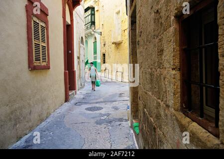 Frau mit einem Beutel in einer Gasse von Birgu (Vittoriosa), Malta Stockfoto