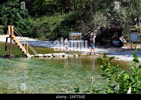 Khorevtón, Griechenland - 21. September 2019: Unbekannter ältere Touristen Kreuzung Flusses Acheron auf provisorische Brücke mit Steinen gebaut, Epirus county Stockfoto