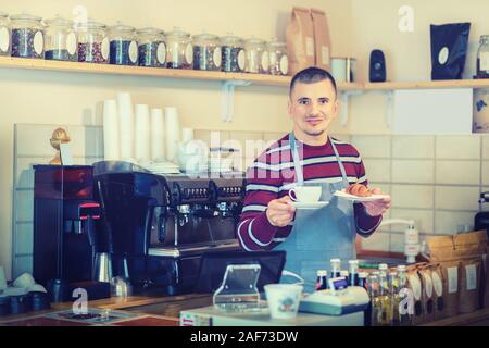 Kellner Frühstück mit Kaffee und Croissants am Zähler in kleinen Cafe Shop Stockfoto