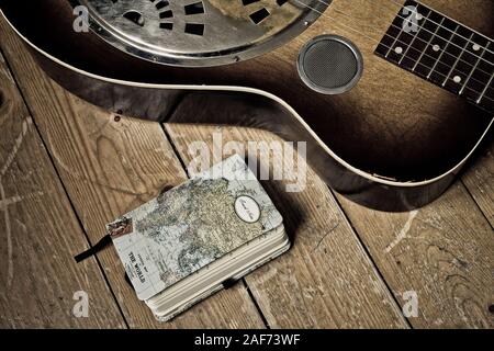 Ein Tagebuch und ein Detail einer Dobro Gitarre auf einem hölzernen Hintergrund Stockfoto