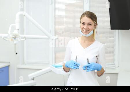 Lächelnd Zahnarzt steht in der Mitte des Schrankes mit Ihrer Maske pullded nach unten. Selektive konzentrieren. Stockfoto