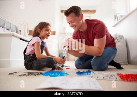 Vater und Tochter im Schlafzimmer Gebäude Roboter Bausatz zusammen Stockfoto