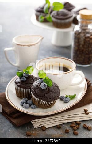 Chocolate Muffins mit frischen Heidelbeeren und Kaffee Tasse zum Frühstück Stockfoto