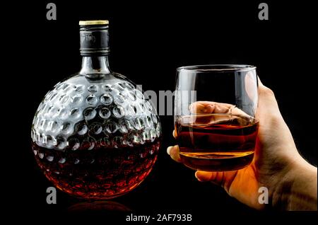 Hand mit Glas Scotch Whiskey Premium und alten Dekanter auf schwarzem Hintergrund Stockfoto