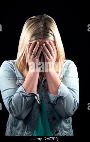 Studio Portrait von Schämen junge Frau mit Gesicht mit den Händen Stockfoto