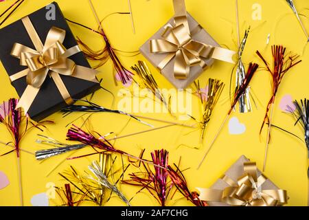 Urlaub Hintergrund. Verschiedene handgearbeitete Geschenkboxen mit rosa Herzen Konfetti auf gelbem Hintergrund eingerichtet. Minimal Style und Valentines Tag Konzept. Fla Stockfoto