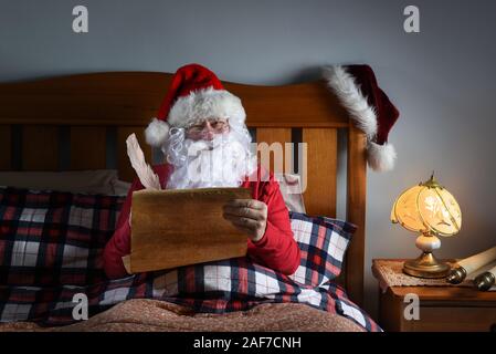 Santa Claus sitzt in seinem Bett an seinen frechen und schöne Liste. Stockfoto