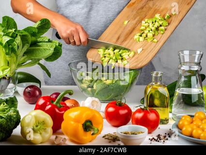 Frau fügt Avocado, Salat in eine Glasschüssel gehackt, Kochen in der Küche. Gesunde Ernährung Konzept. Stockfoto