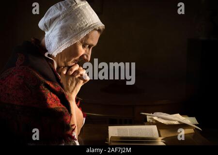 Rembrandt Stil oder Renaissance Porträt einer Frau, die in einem dunklen Raum beten Stockfoto