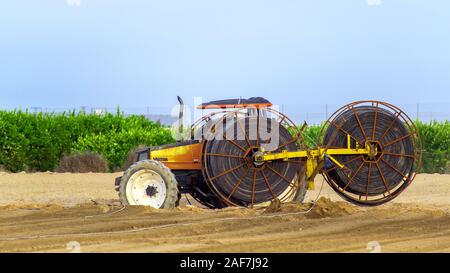 Murcia, Spanien, 12. Dezember 2019: Moderne Maschinen für Bewässerung Rohre in neue Plantage. Traktor im landwirtschaftlichen Bereich in Spanien. Stockfoto