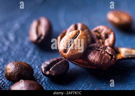 In der Nähe von gerösteten Kaffeebohnen auf einem Haufen auf einem blauen Hintergrund Stockfoto