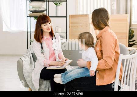 Freundliche junge Frau Kinderarzt Arzt Gespräche mit der Mutter der kleinen Mädchen nach Prüfung. Stockfoto