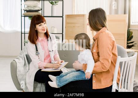 Freundliche junge Frau Kinderarzt Arzt Gespräche mit der Mutter der kleinen Mädchen nach Prüfung. Stockfoto