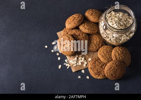 Nützliche leckere Haferflocken in einem durchsichtigen Glas Glas und Haferflocken Cookies auf einem dunklen Hintergrund Stockfoto