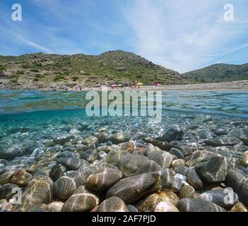 Spanien Mittelmeer, Strand Ufer im Sommer mit Kieselsteinen Felsen unter Wasser, geteilte Ansicht oberhalb und unterhalb der Oberfläche, Costa Brava, El Port de la Selva Stockfoto