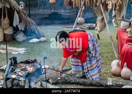 Eine Frau in traditioneller Kleidung kocht Huhn auf einem Feuer im Poarch Creek Indian Thanksgiving Pow Wow Stockfoto