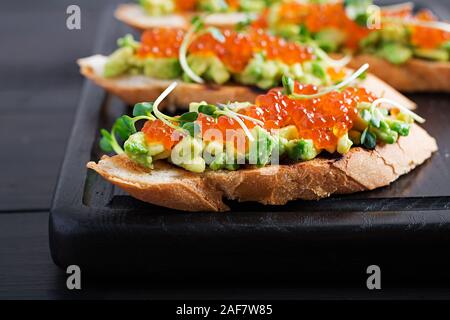 Sandwiches mit Lachs roter Kaviar und Salsa mit Avocado. Sandwich zum Mittagessen. Leckeres Essen. Stockfoto