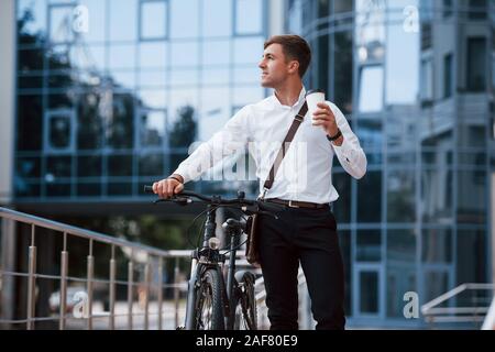 Die Schale mit frischen Getränken. Geschäftsmann in formelle Kleidung mit schwarzen Fahrrad ist in der Stadt Stockfoto