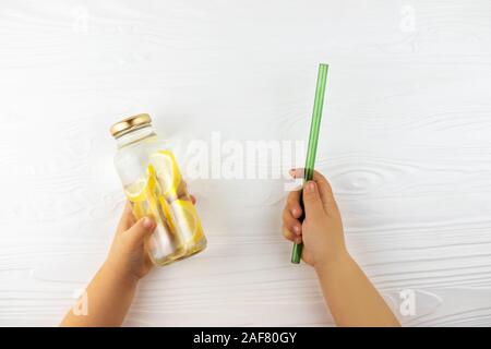 Child's Hände, die Glasflasche mit Limonade und Stroh. Null Abfall Konzept. Stockfoto