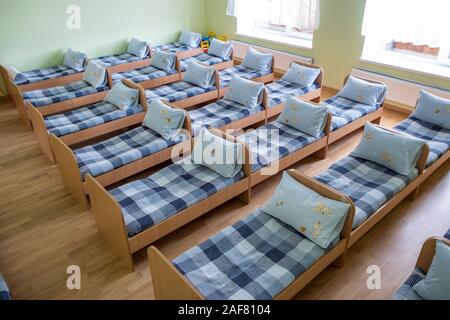 Viele kleine Betten mit frischer Bettwäsche in der Kindertagesstätte Vorschule leere Schlafzimmer Innenraum für komfortable Mittagsschlaf der Kinder. Stockfoto