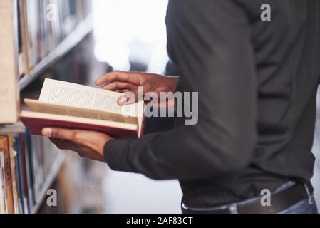 Seiten drehen. Afrikanische amerikanische Mann in der Bibliothek auf der Suche nach einige Informationen in der Bücher Stockfoto