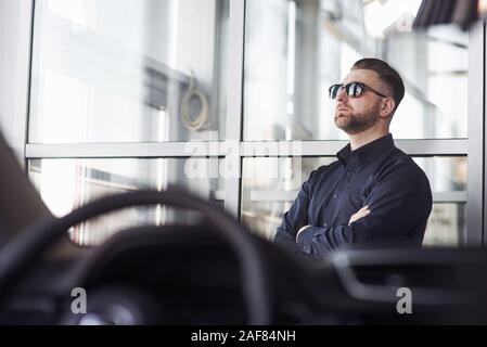 Luxus suchen. Mann in offiziellen Kleidung seinem neuen Auto im Automobil Salon versuchen, Stockfoto