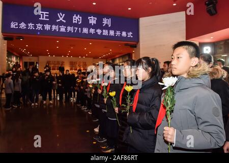 (191213) - Peking, Dez. 13, 2019 (Xinhua) - Studierende bereiten Sie Blumen zu Märtyrer während einer Ausstellung an der Tokioter Prozess im Museum für den Krieg der Chinesen, der Widerstand gegen die japanische Aggression in Peking, der Hauptstadt von China, Dez. 13, 2019 präsentieren. Vor der Masse in Schwarz, Chinas nationale Flagge flog auf Halbmast als die Nation einer Trauerfeier Freitag statt der 300.000 Opfer des Massakers von Nanjing zu trauern. (Xinhua / Peng Ziyang) Stockfoto