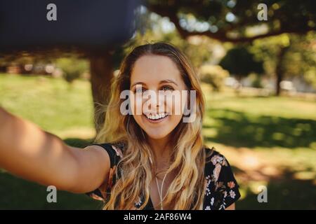Portrait Of Happy schöne junge blonde Frau eine selfie im Park an einem sonnigen Tag Stockfoto