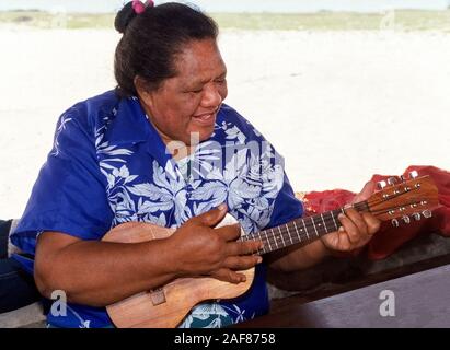 Ein Gebürtiger Hawaiianer Frau unterhält mit Lied und Ihr ukelele ein paar Besucher auf Niihau, eine isolierte Pazifik Insel in Hawaii, USA. Es ist, als die verbotene Insel bekannt, weil nur Niihauans auf der Insel geboren erlaubt, dort zu leben und Touristen sind zu einem Helikopter Ausflug seinen Ufern nur für ein paar Stunden zu besuchen begrenzt sind. Privat im Besitz der gleichen Familie seit Sie es vom König von Hawaii im Jahre 1864 erworben haben, ist die 72-square-mile (187 Quadratkilometer) Insel hat weniger als 170 Einwohner und ist die Erhaltung der traditionellen hawaiianischen Kultur gewidmet. Stockfoto