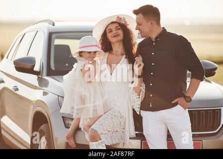 Familie Foto. Leute haben eine gute Zeit an Land in der Nähe von Silber Automobil bei Sonnenuntergang Stockfoto