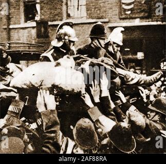 Seige of Sidney Street - die Belagerung der Sidney Street (Januar 1911), auch bekannt als die Schlacht von Stepney, nahm am East End von London zwischen der britischen Polizei von Soldaten unterstützt, nach einem Raub und der Ermordung von drei Polizisten durch lettische revolutionäre. Dieses historische Foto zeigt Feuerwehrmänner und Polizisten, die nach der Veranstaltung das brennende Gebäude besuchen. Stockfoto