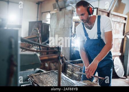 Sicherheit der Anhörung. Mann in Uniform Werke auf die Produktion. Die industrielle moderne Technologie Stockfoto