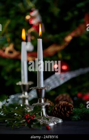 Brennende Kerzen in Antik Silber Kerzenleuchter mit geschmückten Weihnachtsbaum im Hintergrund. Stockfoto