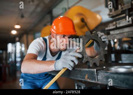 Gelb gefärbte Maßband. Mann in Uniform Werke auf die Produktion. Die industrielle moderne Technologie Stockfoto