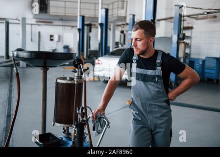 Beruf des Mechanikers. Man spezielle Gerät gebrochen Auto in der Garage zu reparieren. Stockfoto