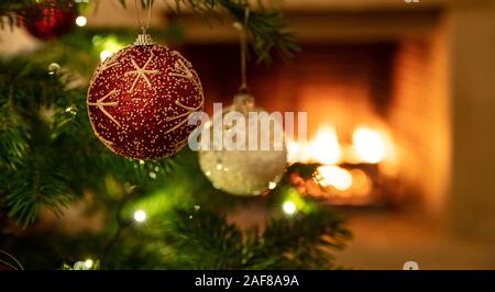 Weihnachtsbaum, Kamin Hintergrund. Warme gemütliche Weihnachten Ferienhaus. Weihnachtskugeln closeup, Blur brennenden Kamin, Kopie Raum Stockfoto