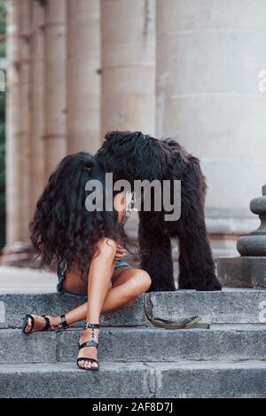 Spielt mit Hund. Schöne Frau mit lockigem Haar haben eine gute Zeit in der Stadt am Tag Stockfoto