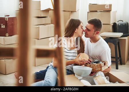 Auspacken des Kartons. Fröhlicher junger Paare in der neuen Wohnung. Konzeption von verschieben Stockfoto