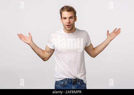 Das, was Sie wollen. Verwirrt und leichtsinnig gutaussehenden Blonden kaukasischen Kerl Verbreitung Hände seitlich befragt, achselzuckend Fragen stellen, kann nicht verstehen, nicht Stockfoto