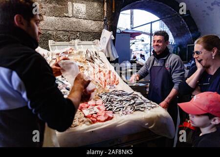 Zufriedene Verkäufer und Käufer in der Nähe einer Markttheke in Piscaria Mercato del Pesce Stockfoto