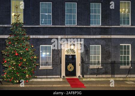 Downing Street geschmückter Weihnachtsbaum, Türkranz und roter Teppich außen, London, Westminster, Großbritannien Stockfoto