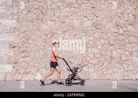 Junge Mutter mit dem Kinderwagen für Ihr Baby nach der Geburt in Form zu bleiben. Stockfoto