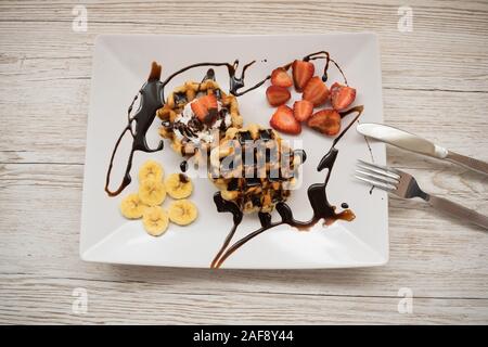 Blick von oben auf die Waffeln mit Obst und Schokolade auf einer Platte Stockfoto