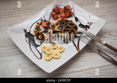 Leckere Waffeln mit Schokolade Früchte auf einem Holztisch Stockfoto